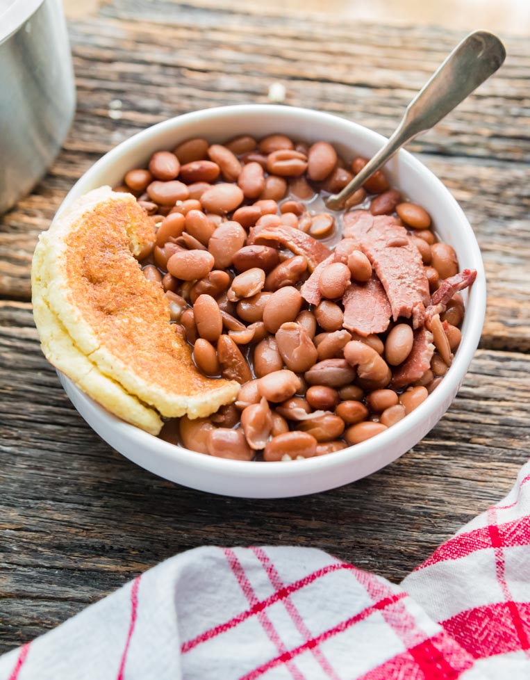 a bowl of pinto beans with cornbread and  spoon 