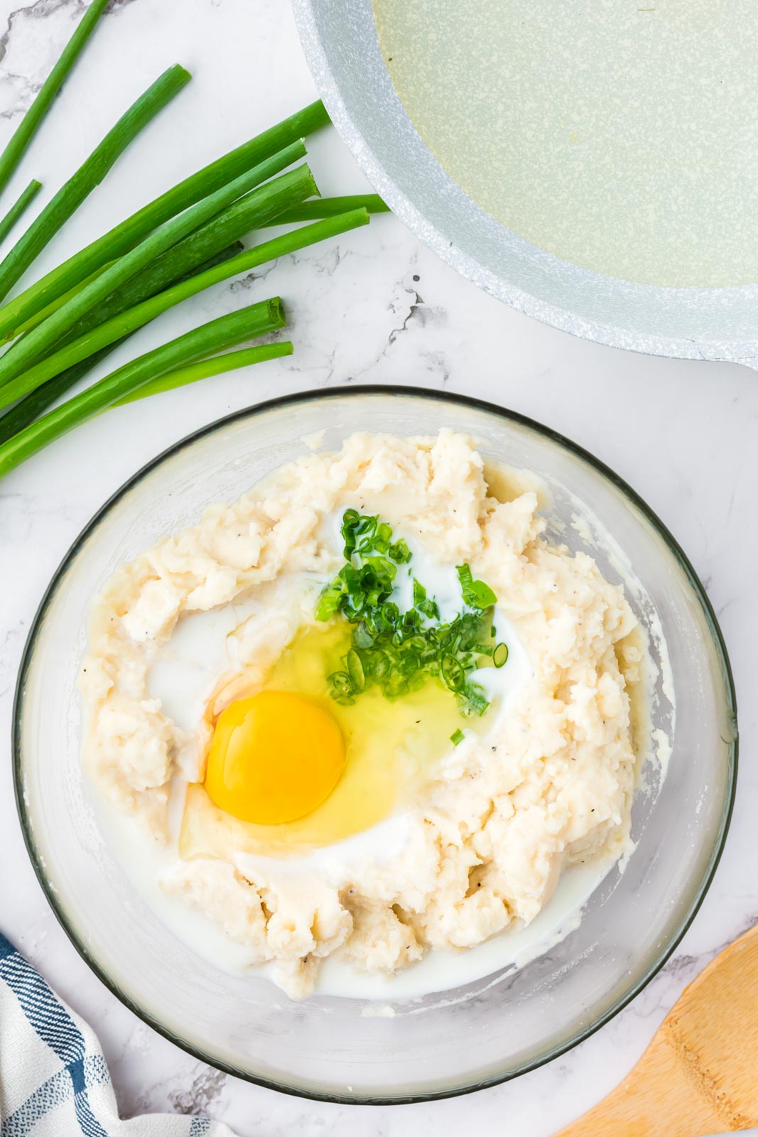 a bowl of mashed potatoes with an egg and green onions 