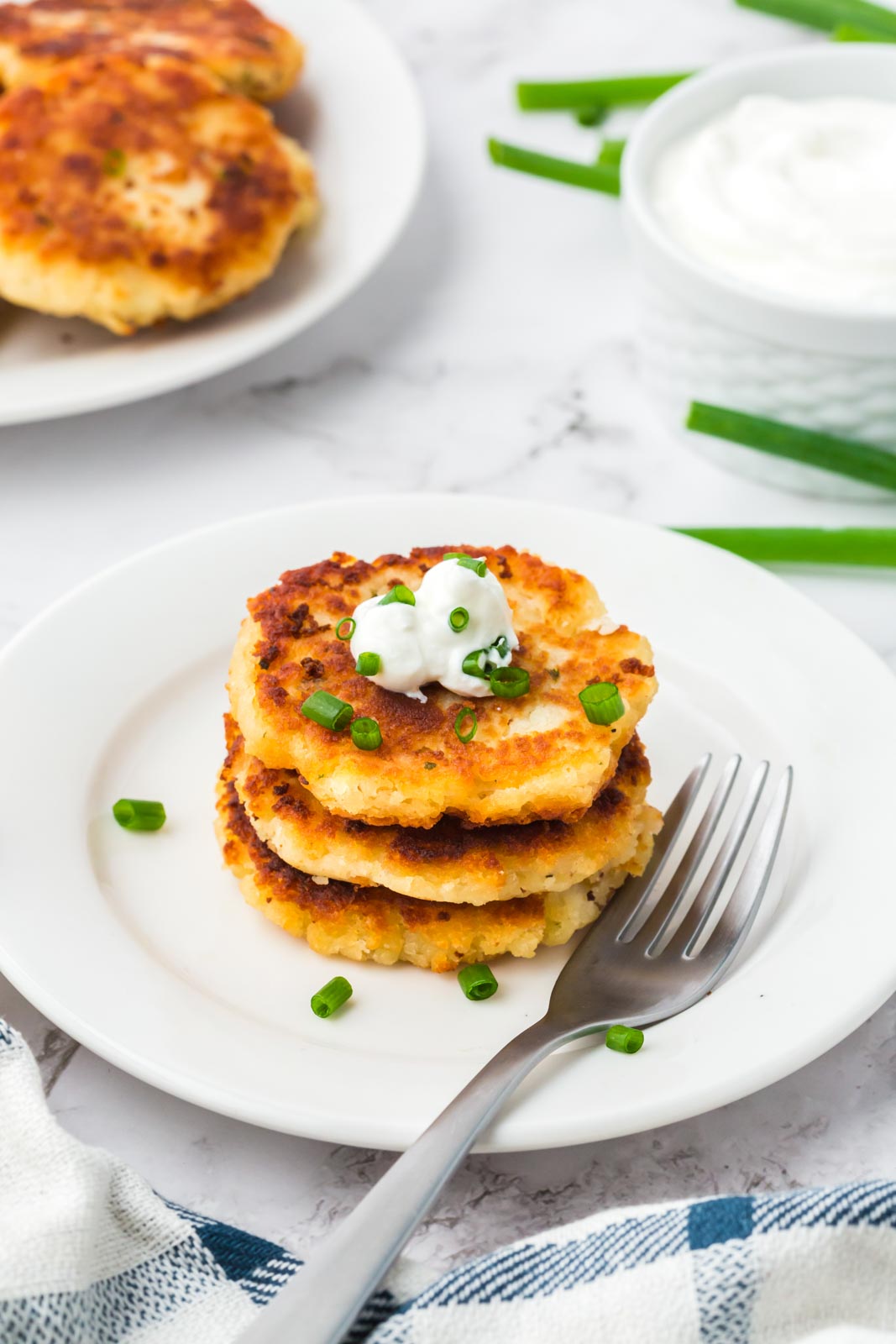 a plate of mashed potato cakes with sour cream
