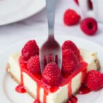 A fork taking a bite of raspberry cheesecake.