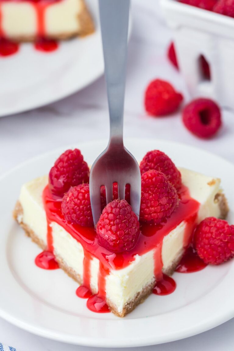 A fork taking a bite of raspberry cheesecake.