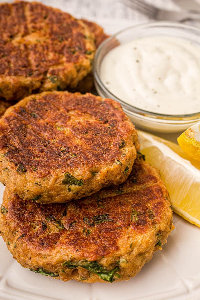 salmon patties on a plate with lemons and sauce