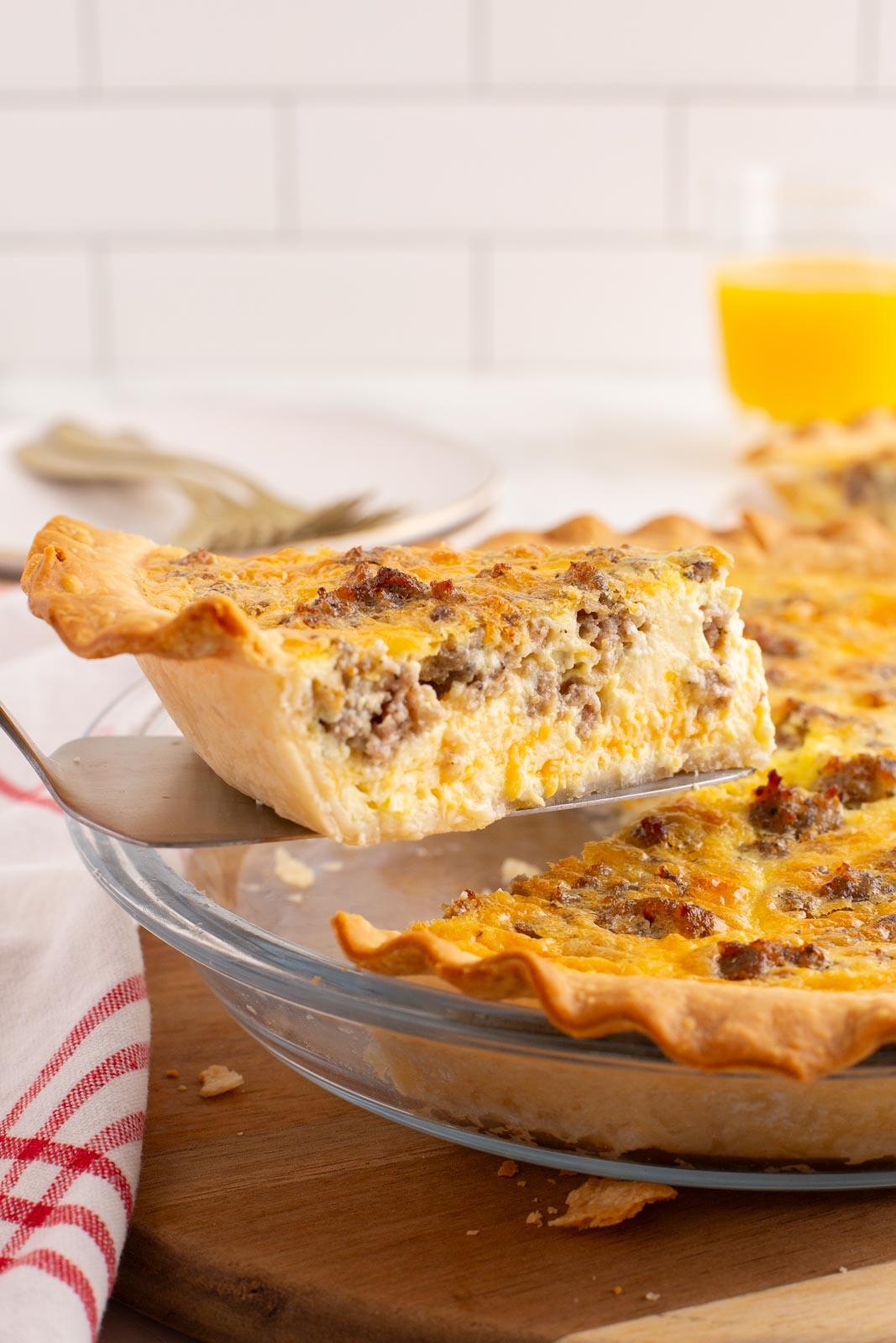 a slice of sausage quiche being lifted from a pie plate with a spatula 