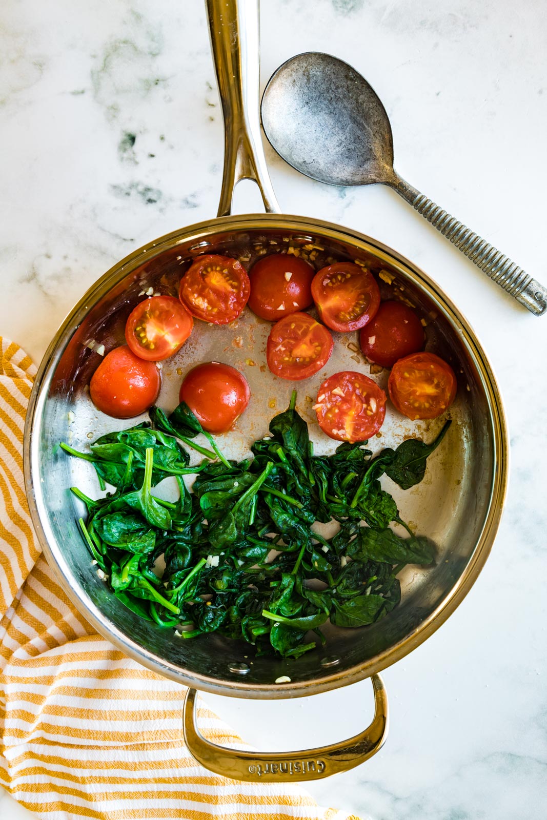a skillet with sauteed tomatoes and spinach 