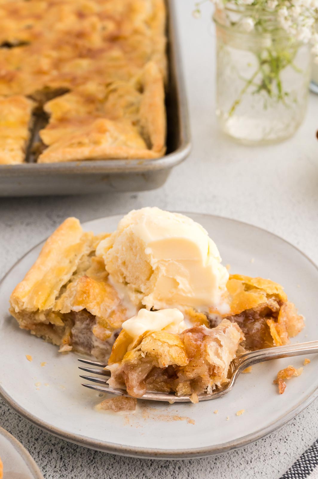 a slice of apple slab pie on a plate with ice cream and a fork 