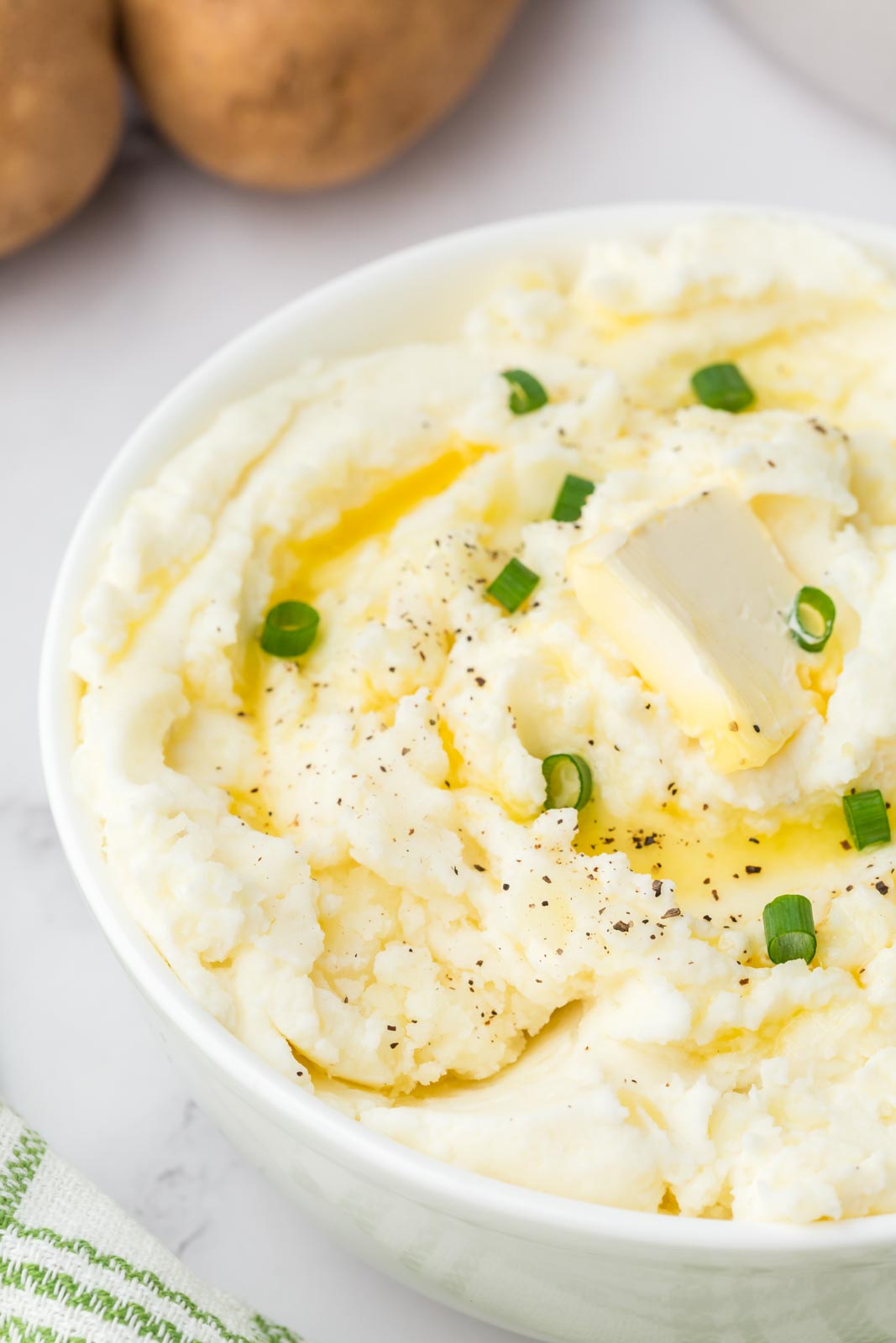 a bowl of mashed potatoes with chives and butter on top