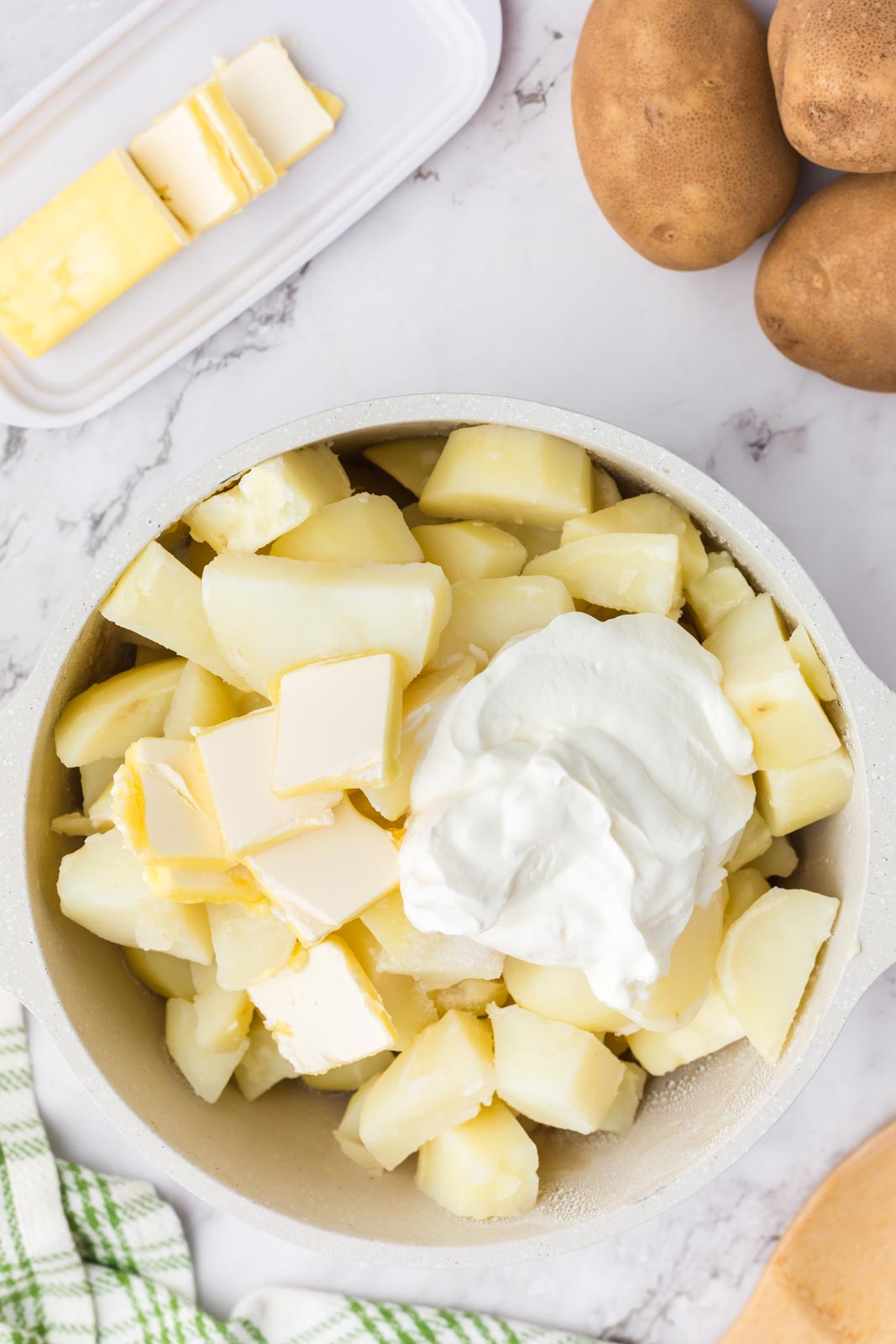 a pot of boiled potatoes with butter and sour cream on top 
