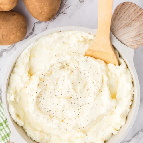 a bowl of sour cream mashed potatoes with a spoon in the bowl