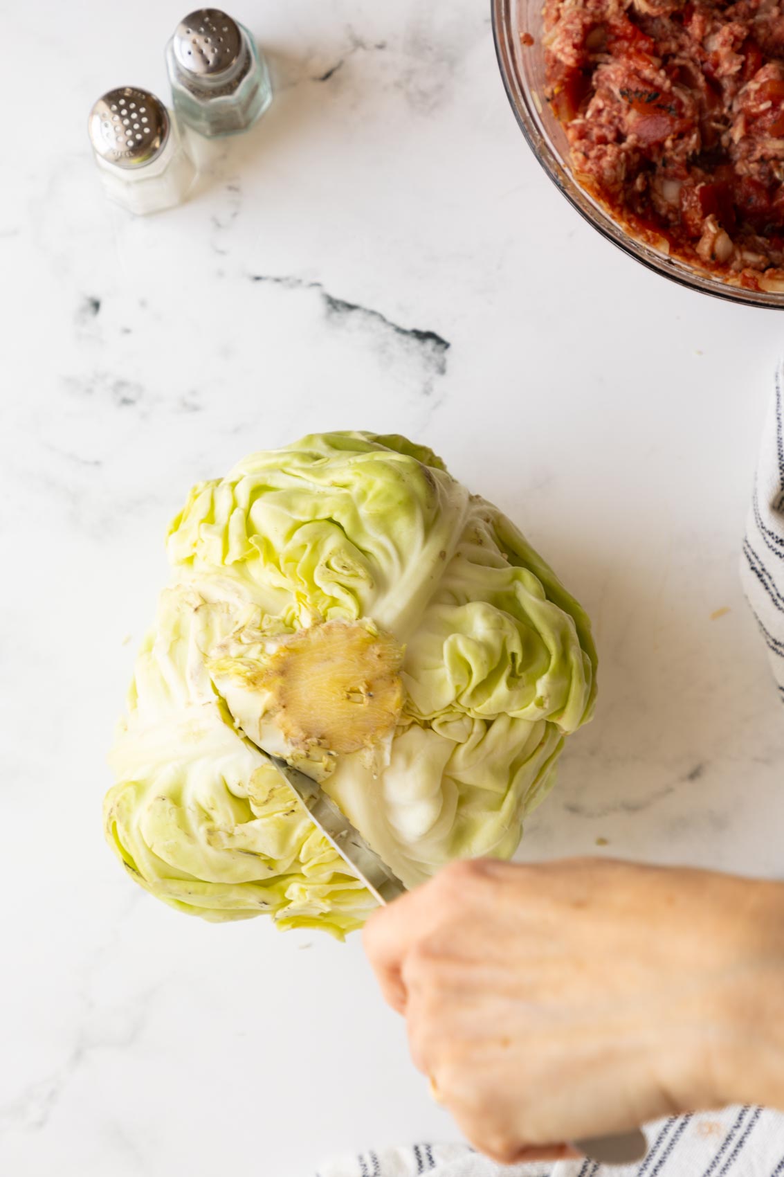 a head of cabbage, core end up with a knife cutting out the core