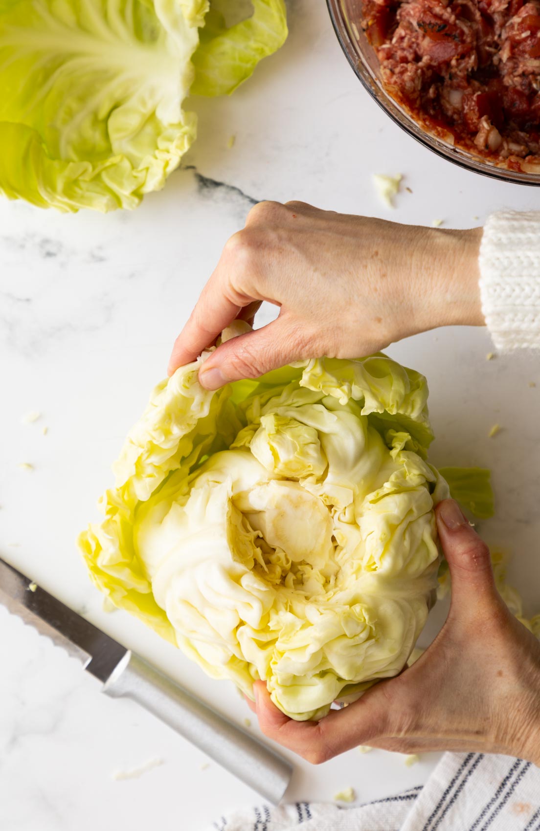 a hand separating cabbage leaves from the core 