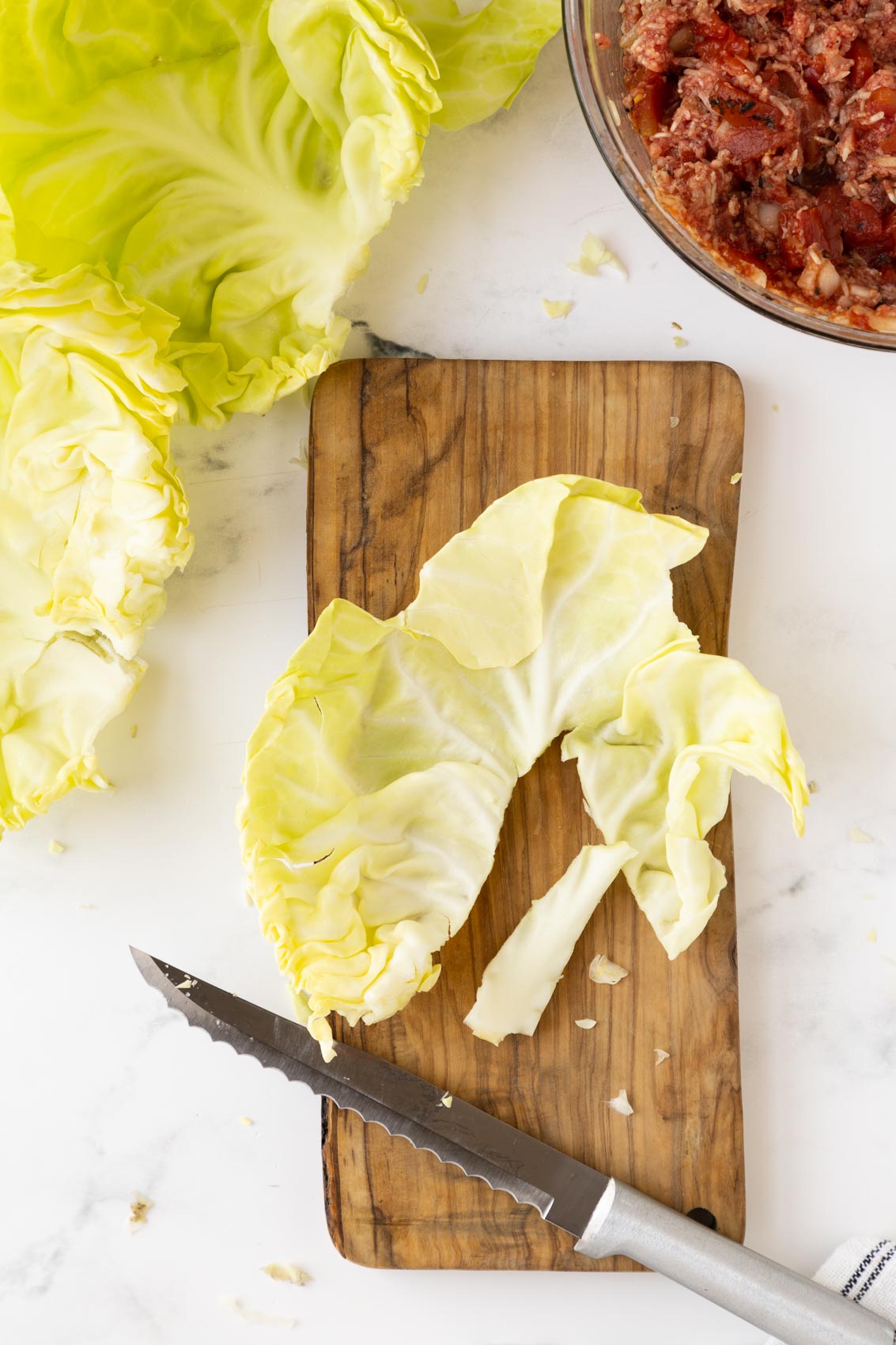 a cabbage leaf on a cutting board with the thick stem removed