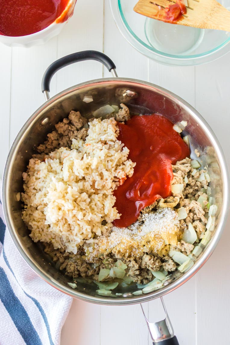 a skillet with rice, tomato sauce and cooked pepper fillings 