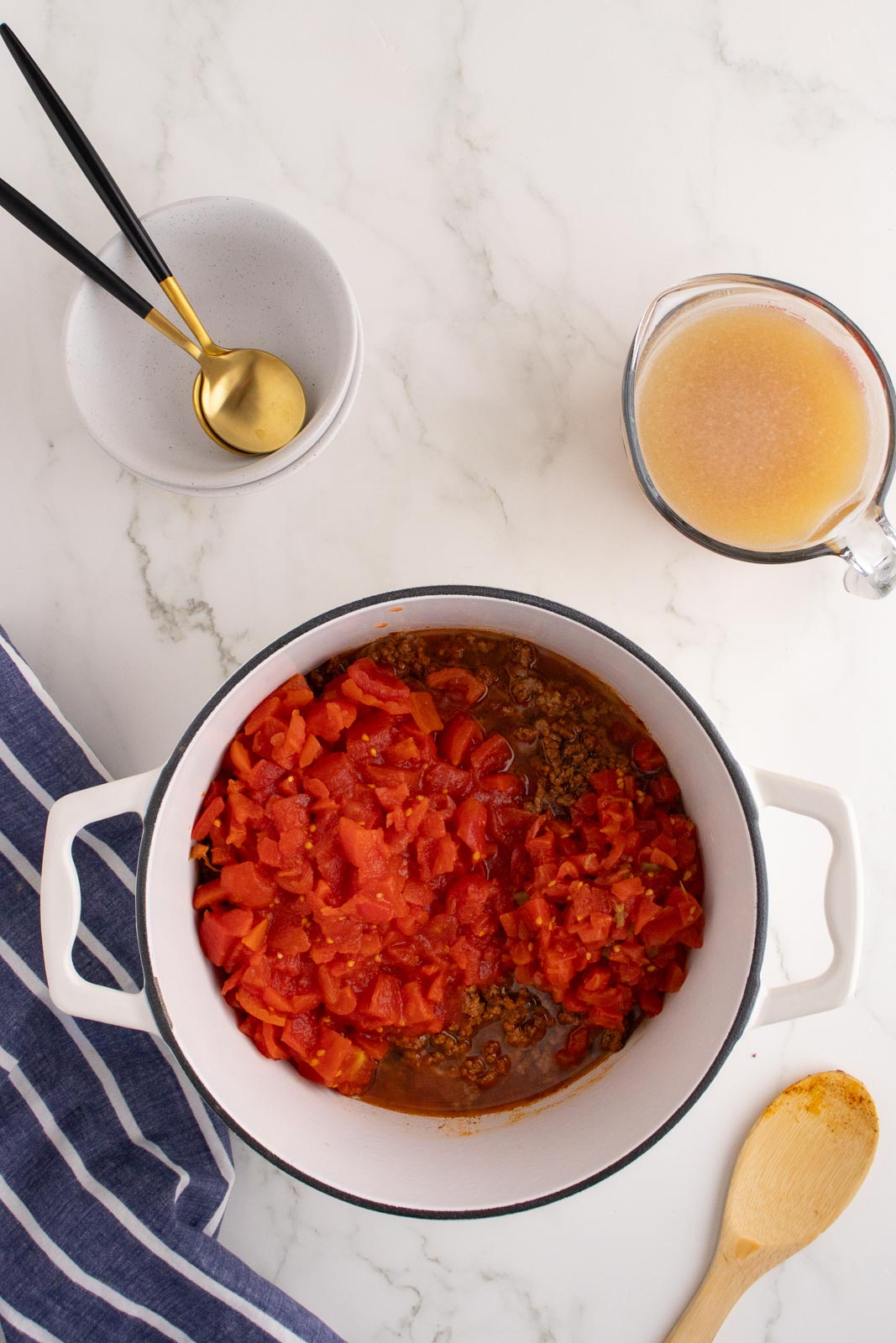 a pot of soup with diced tomatoes added ground beef 
