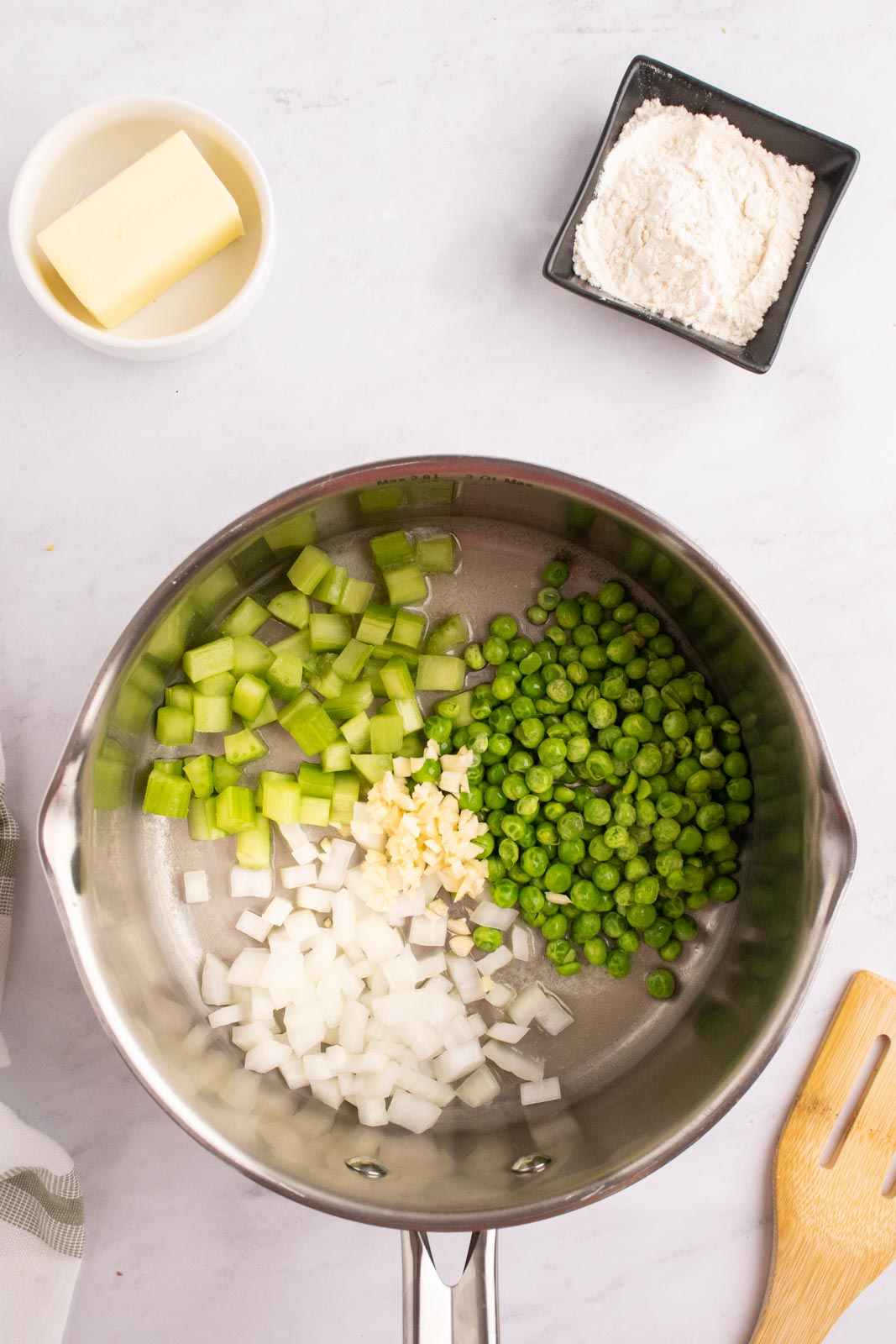 Onion, celery, garlic, and peas in a pan.