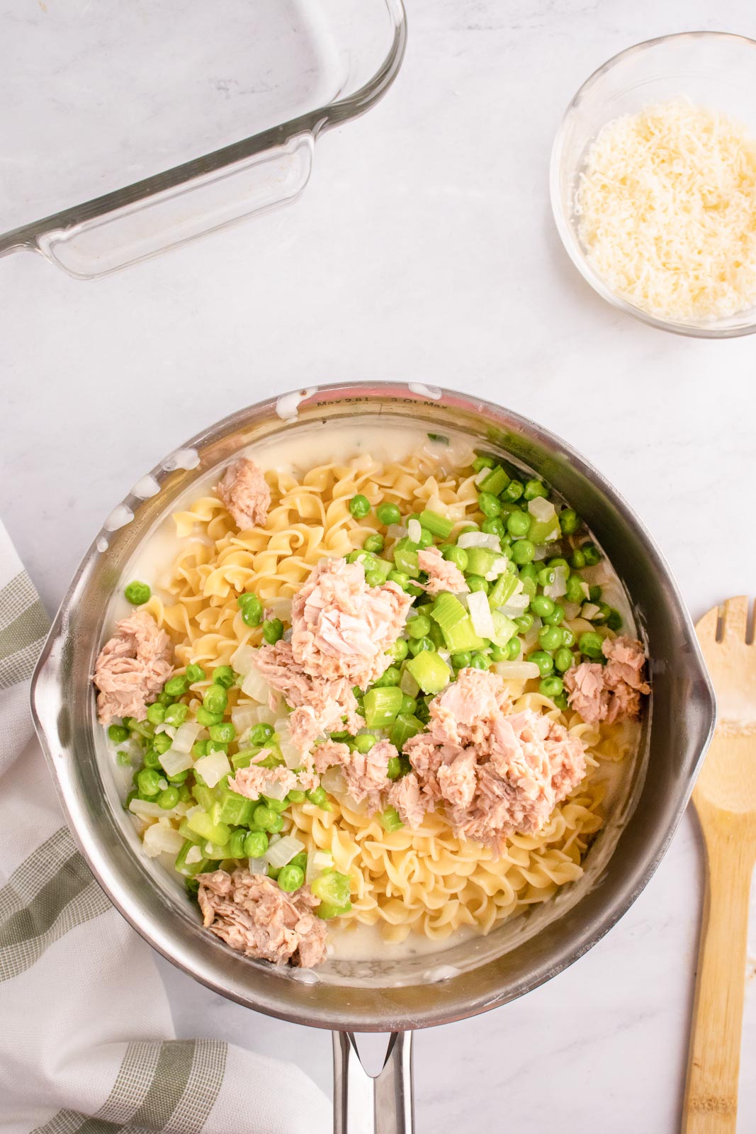 Adding tuna, egg noodles, and sauteed veggies to cream sauce for tuna noodle casserole.