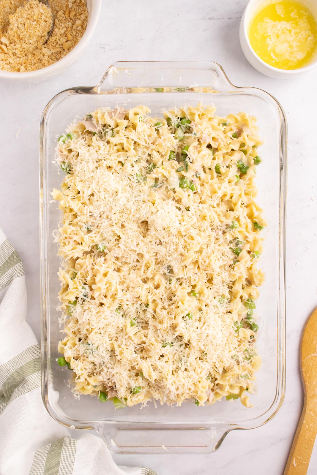 Adding parmesan and crumbled Ritz crackers to the top of tuna noodle casserole.