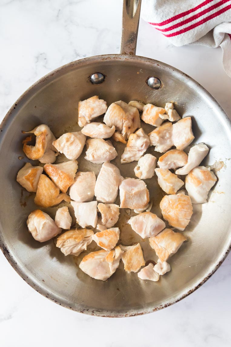a skillet of cubed chicken breast being seared