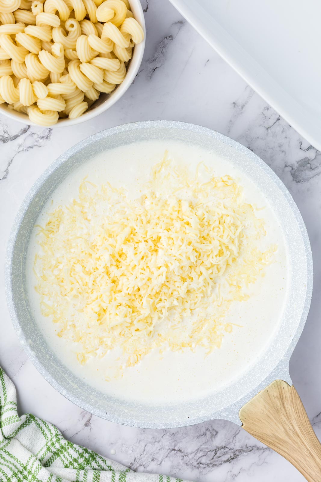 Adding parmesan to white sauce to make baked white mac and cheese.