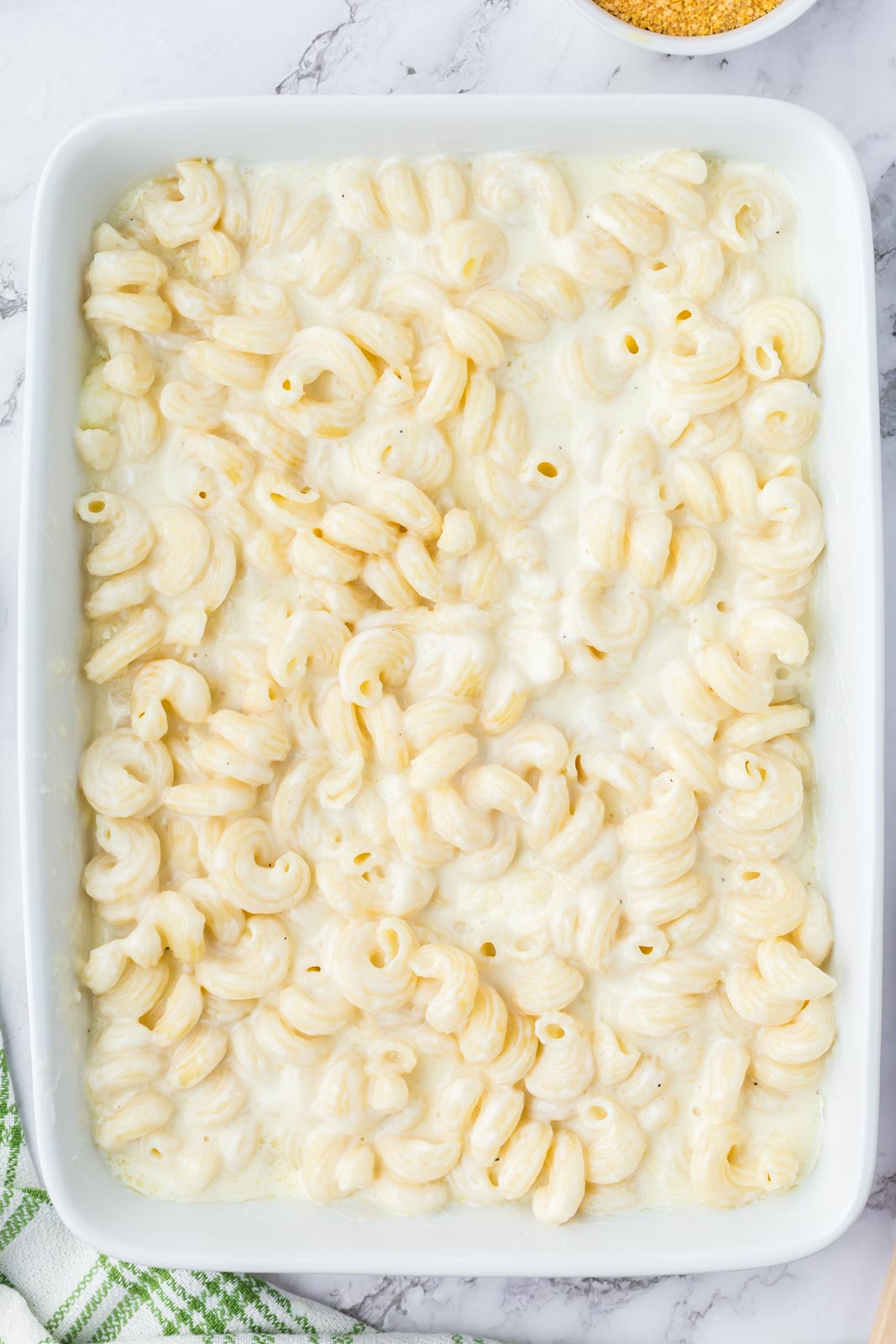 White mac and cheese in a casserole dish ready to be baked.