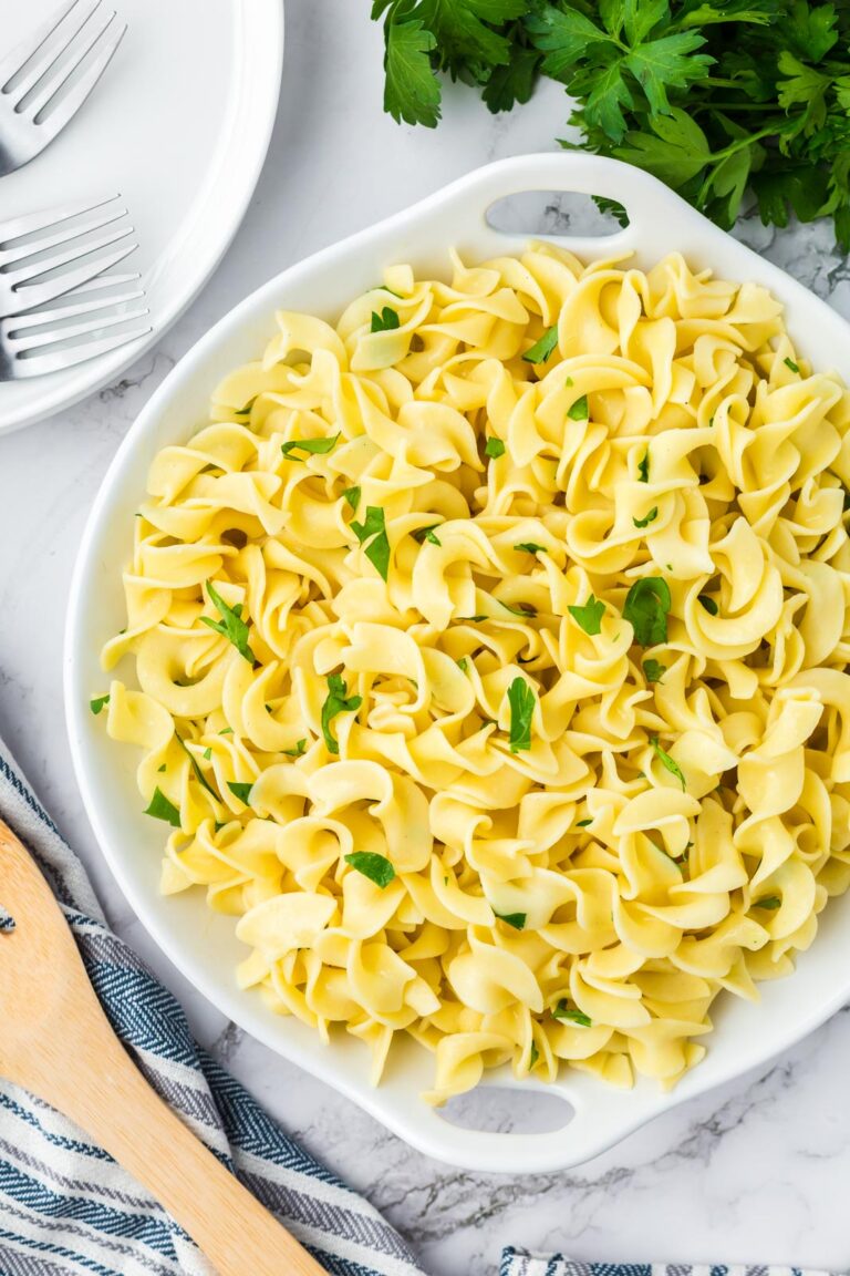 a bowl of egg noodles n a table with serving plates and forks
