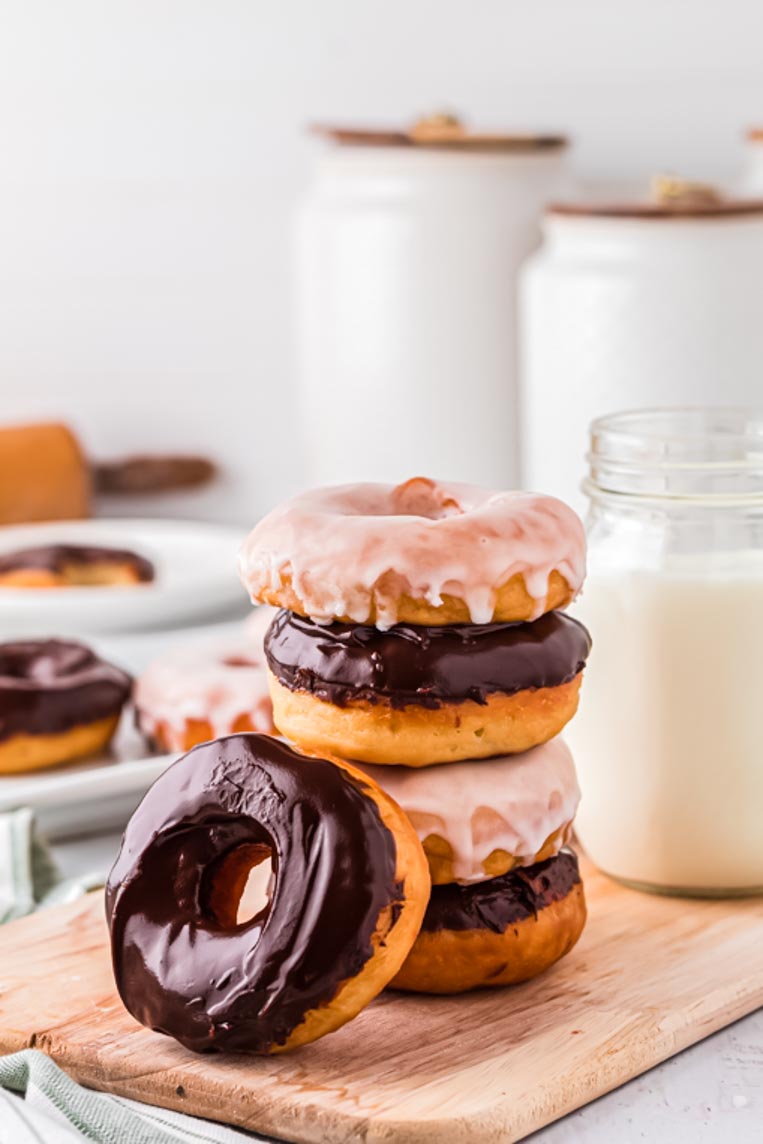 three stacked donuts and one chocolate glazed donut leaned against them on a table
