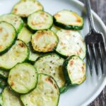 a plate of roasted zucchini slices on a plate with a fork