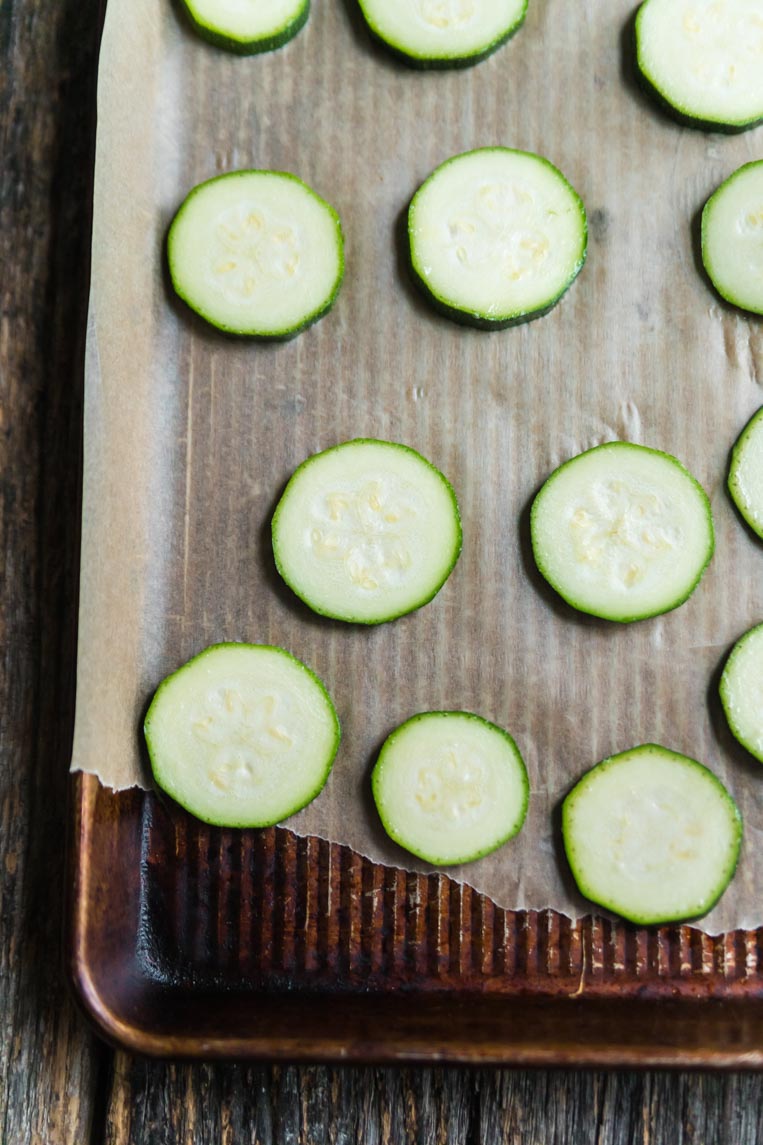 a cookie sheet with parchment paper and slices of zucchini