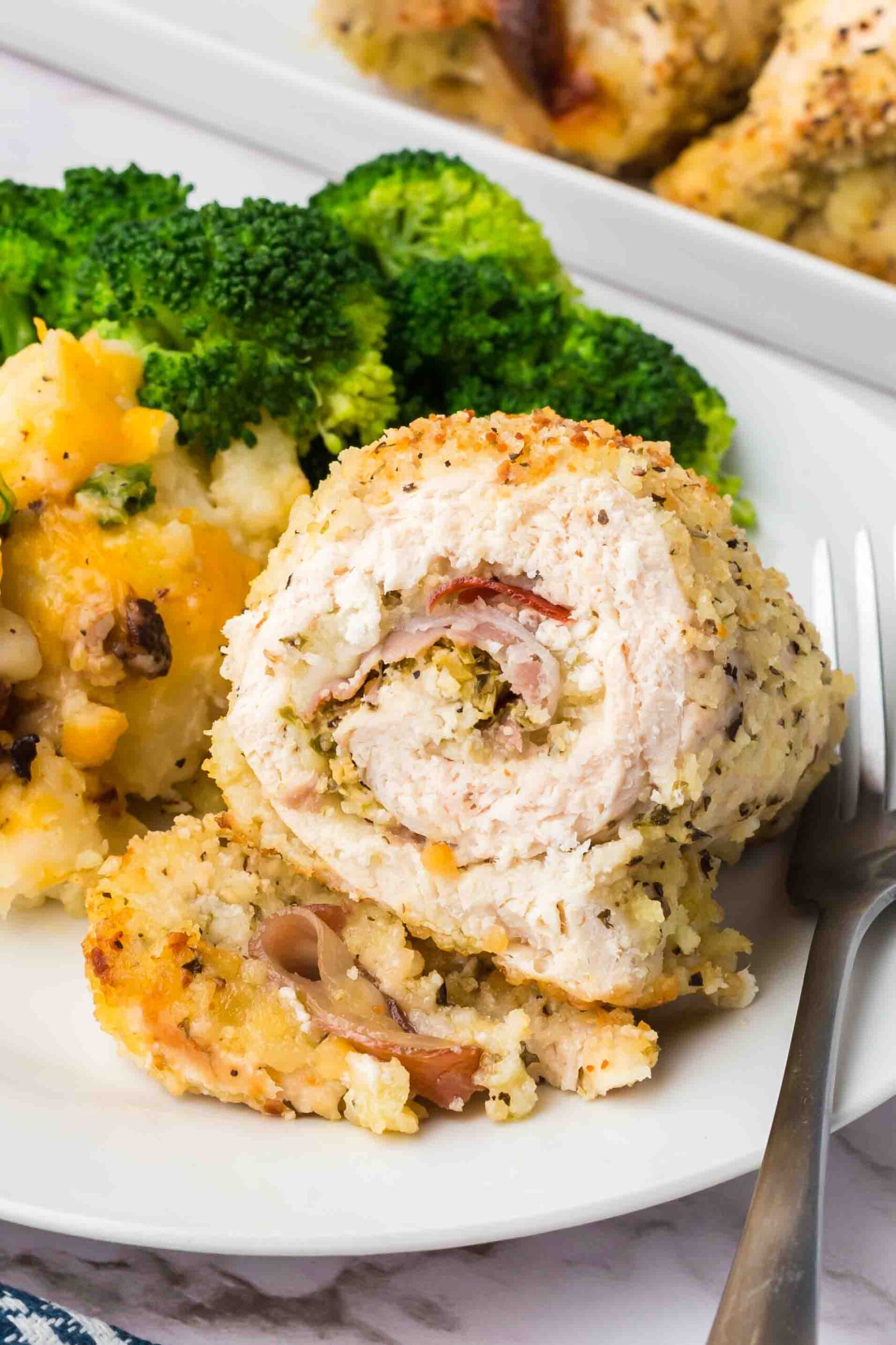 a sliced chicken rollatini on a plate with broccoli 