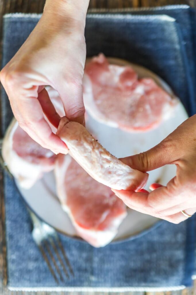 a pork chop held sideways to show its thickness