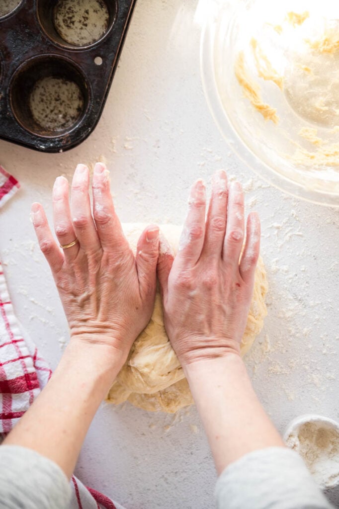Two hands using the heel of the hands to press into the dough 