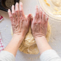 two hands gently pressing the dough away from the body.