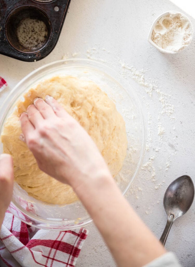 Closed fingers and a cupped hand gently releasing dough from a bowl onto a countertop
