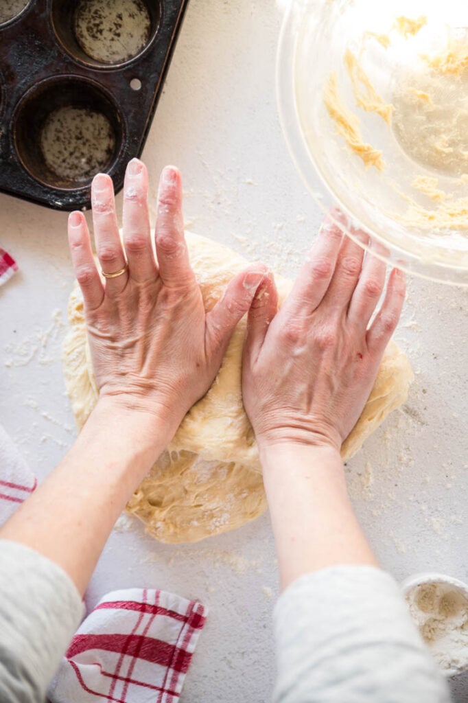 Two hands using the heel of the hands to press into the dough