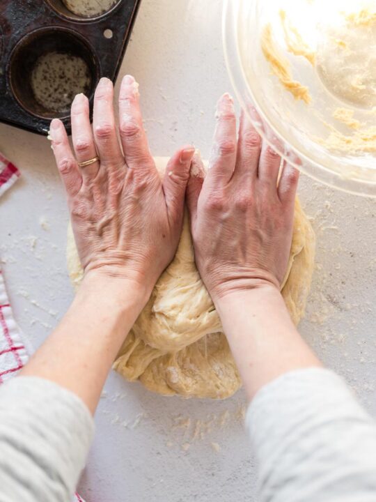 Two hands using the heel of the hands to press into the dough