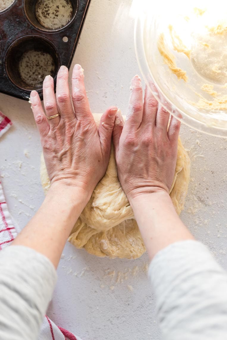 Two hands using the heel of the hands to press into the dough 