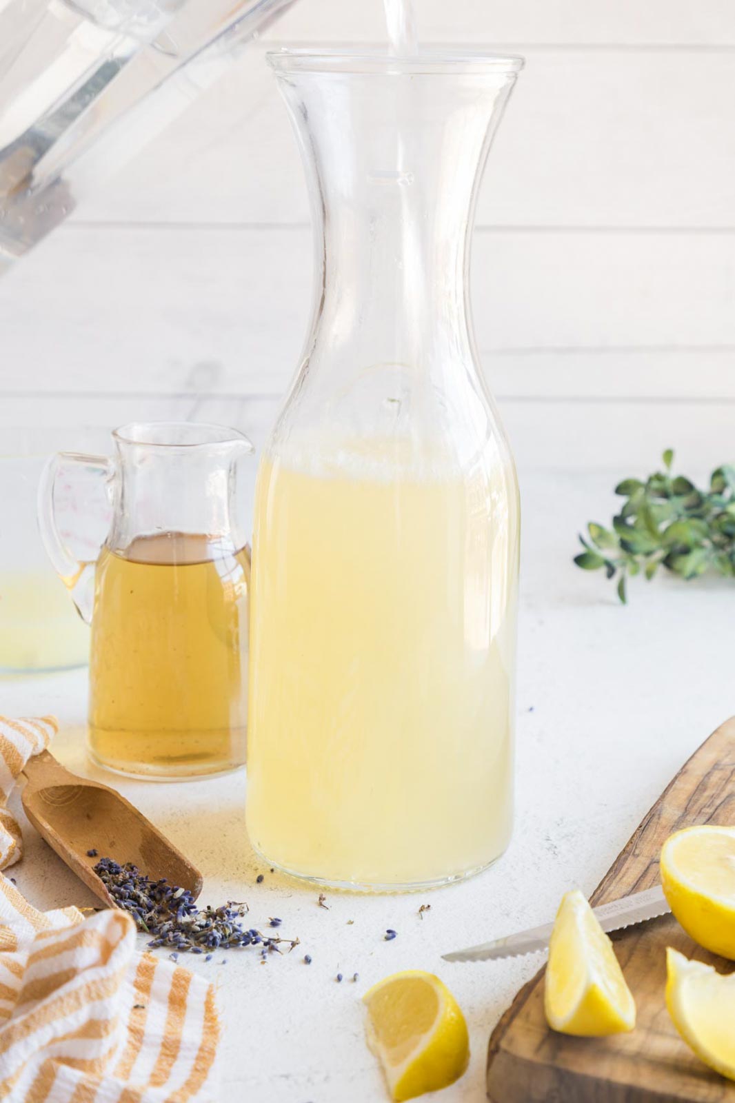 Adding water to a pitcher with lavender lemonade base.