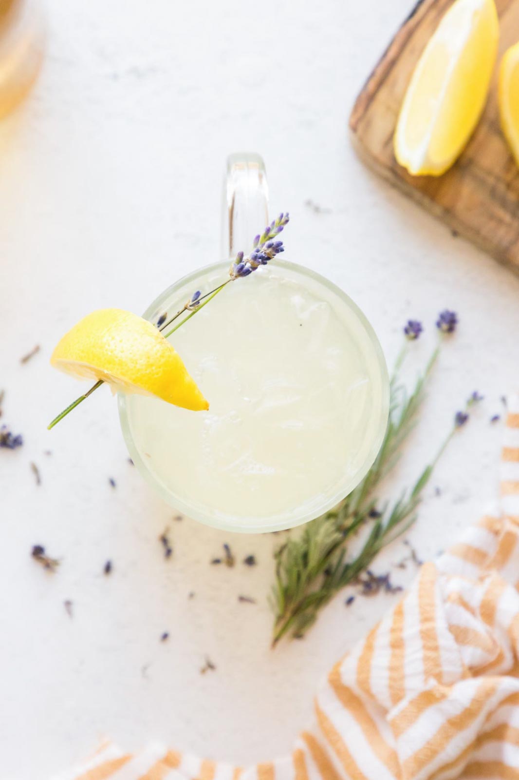 Overhead image of iced lavender lemonade in a glass garnished with fresh lavender and a lemon wedge.