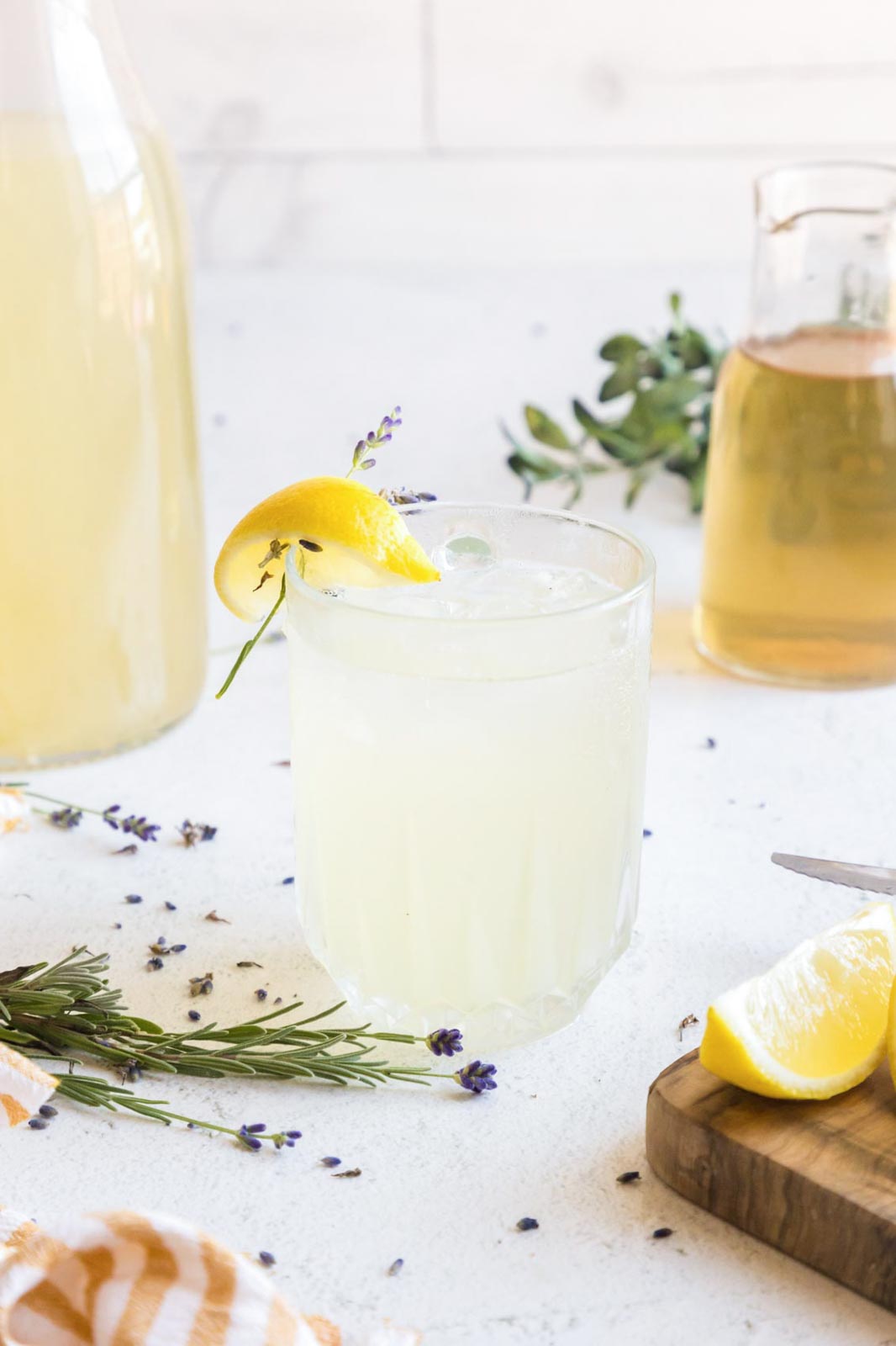 Iced lavender lemonade in a glass garnished with fresh lavender and a lemon wedge.