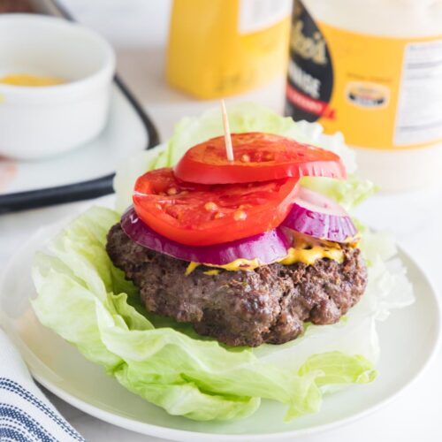a bunless burger on a table with mayonnaise and mustard in the background