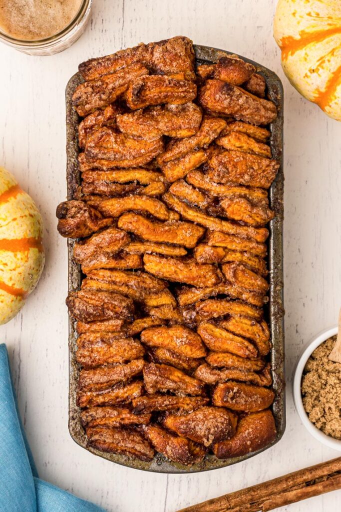 a baked loaf of pull apart bread with pumpkin on a white table