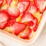 corner of a baking dish overlooking strawberries on top of casserole
