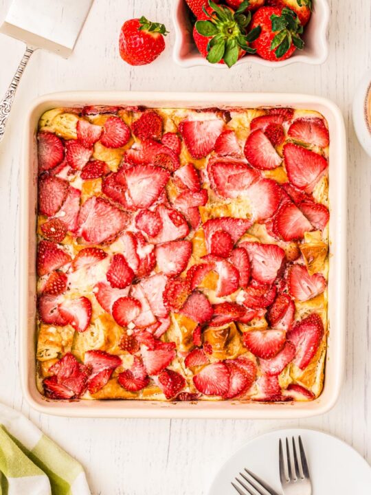 A baked 8x8 pan of croissant breakfast casserole on a table