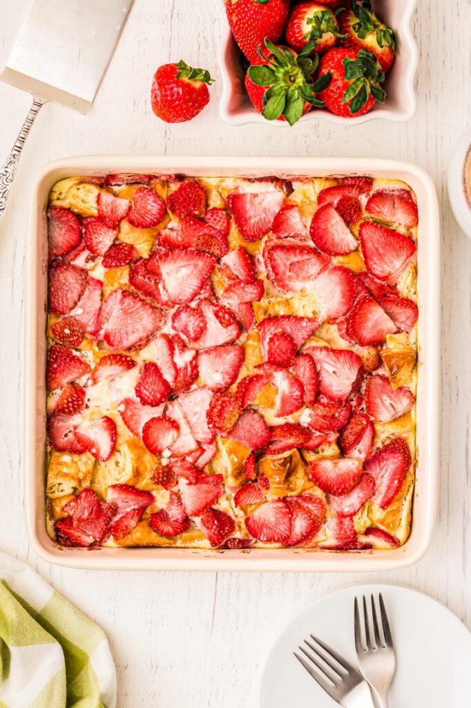 A baked 8x8 pan of croissant breakfast casserole on a table 