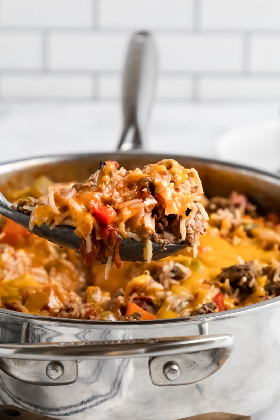 a spoon holding a scoop of cooked stuffed pepper casserole topped with cheese