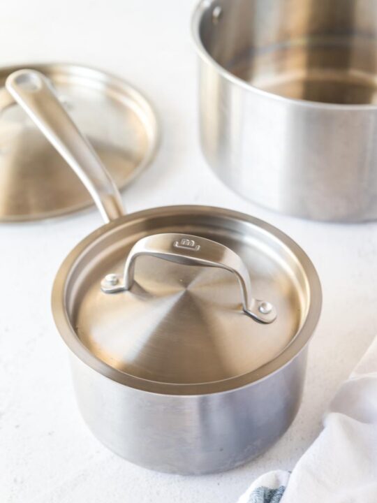 three stainless steel cookware pieces on a table