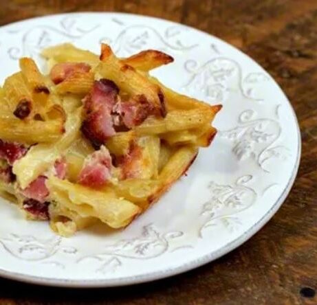 cheesy penne pasta and ham on a plate on table