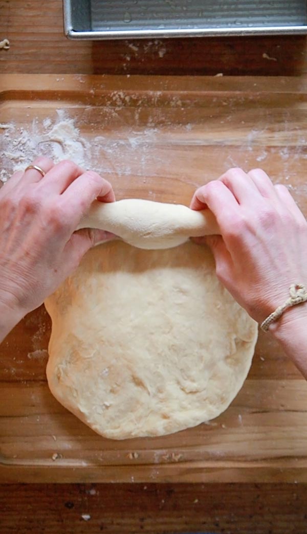 two hands rolling up dough 