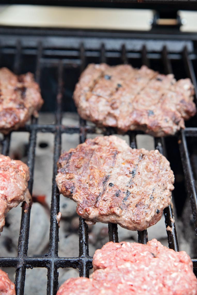 hamburger patties cooking on a grill 