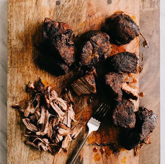 pull pork roast pieces on a cutting board with a fork 
