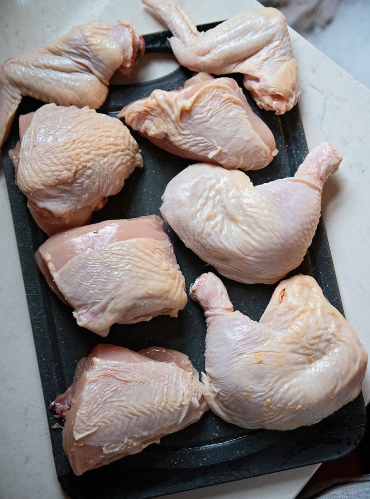 a cutting board of 8 pieces of cut up chicken